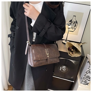 Dettaglio di una borsa a tracolla vintage in pelle marrone con chiusura in metallo su modella