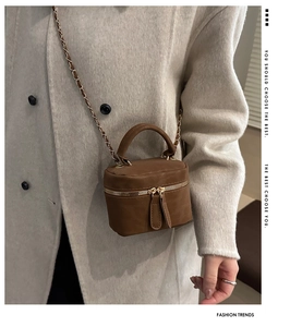 Detail of vintage brown mini box crossbody bag worn with a white cashmere coat