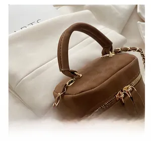 Detail of brown mini bucket bag showing matte leather texture and gold chain strap