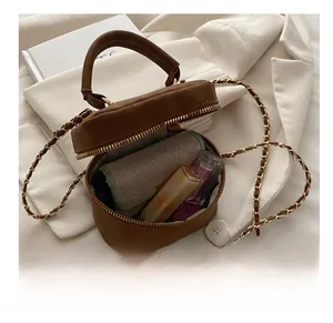 Detail showing internal capacity of the brown suede circle bag with gold chain strap