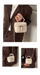 Detail van de crème crossbody tas met rond handvat en metalen ketting schouderband