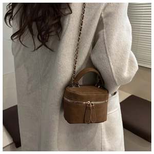 Detailed view of the brown quilted leather mini box bag with gold chain strap on a coat