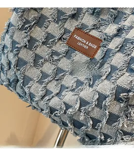 Close-up of checkered denim fabric with distressed fringe edges and brown leather tag