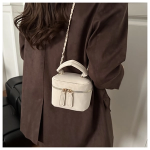 Chic cream mini box crossbody bag with gold chain strap shown on a wool coat