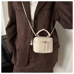 Detail of beige suede mini crossbody bag with gold chain strap and dual zippers