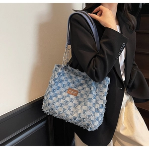 Détail du cabas en denim à damier bleu avec bords effilochés et bandoulière en chaîne