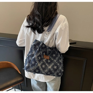 Détail du sac cabas en denim à motif d'étoiles avec bords effilochés et chaîne