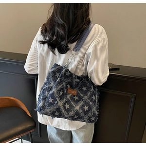 Close-up of star pattern denim tote bag with frayed edges and fashion leather label