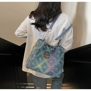 Détail du sac cabas en jean à motifs étoiles avec bords effilochés et chaîne argent