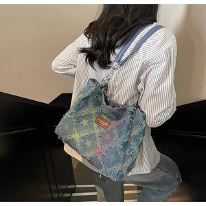 Close-up of distressed denim tote bag with colorful star prints and frayed edges details