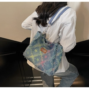 Close-up of denim star pattern tote bag with frayed edges and leather brand tag detail