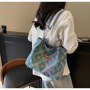 Détail d'un sac cabas en denim avec patchwork d'étoiles effilochées et étiquette cuir