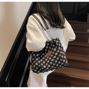 Detail of checkered tote bag with fringe texture, leather straps, and silver chain