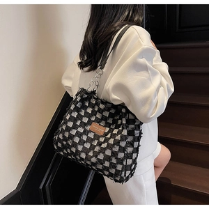 Détail du sac cabas à carreaux avec bords effilochés et bandoulière chaîne en cuir