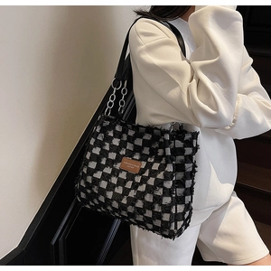 Detail of checkered tote bag with frayed edges and luxury metal chain leather strap