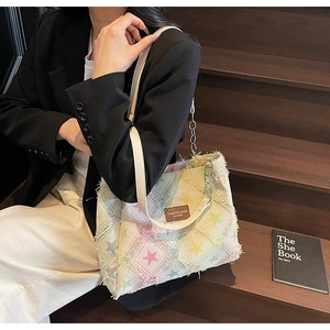 Close-up of star pattern tote bag with distressed fringes and leather strap details