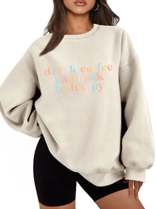 Detail eines Oversize-Sweatshirts in Creme mit buntem Drink Coffee Read Books-Aufdruck