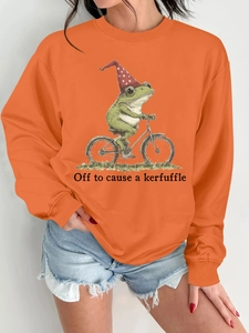 Détail du sweat orange avec imprimé grenouille à vélo et slogan humoristique
