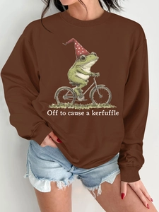 Détail du sweat-shirt marron avec une illustration de grenouille à vélo et texte