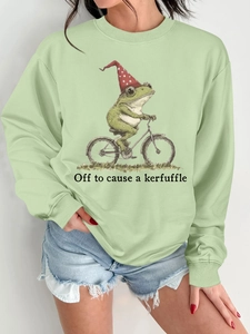 Détail du sweat vert sauge avec motif de grenouille à vélo et slogan humoristique