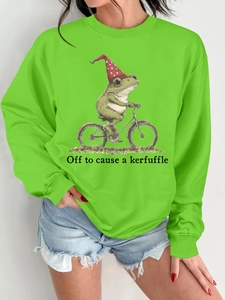 Détail d'un sweat à col rond vert avec illustration humoristique de grenouille à vélo