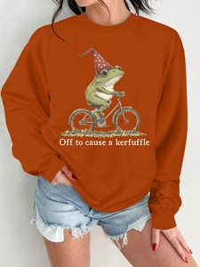 Détail du sweat orange avec imprimé grenouille à vélo et texte humoristique anglais