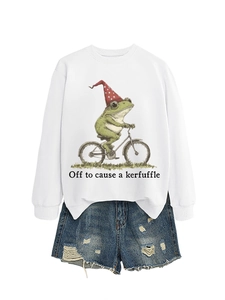 Détail de l'illustration de grenouille à vélo imprimée sur un sweat blanc à col rond