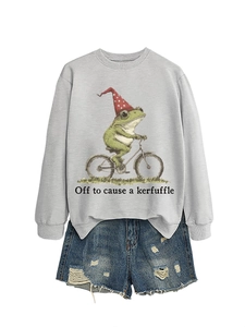 Détail d'un sweat gris avec une illustration de grenouille à vélo et texte amusant