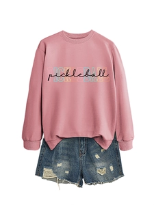 Detailed flat lay of a pink crewneck pickleball sweatshirt paired with distressed denim shorts