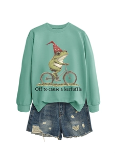 Détail du sweat vert sauge avec grenouille à vélo et ensemble de shorts en jean usé