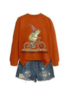 Détail du sweat orange avec imprimé grenouille et short en jean bleu délavé