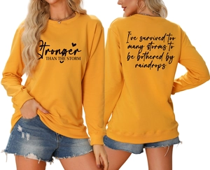 Detail view of yellow crewneck sweatshirt with 'Stronger THAN THE STORM' print and back text