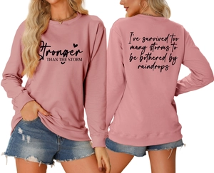 Detail view of pink crewneck sweatshirt with Stronger Than The Storm text print