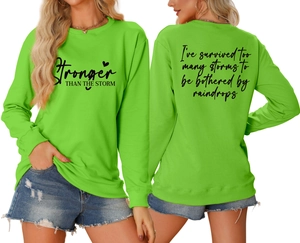 Neon green sweatshirt detail showing Stronger THAN THE STORM front print and back text