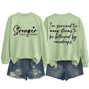 Detail of light green sweatshirt with printed motivational text and distressed denim shorts