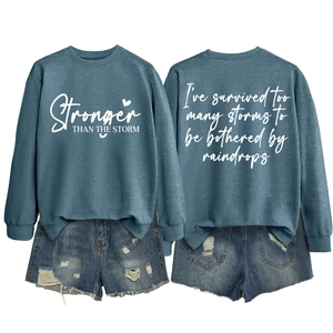 Detail of teal crewneck sweatshirt with Stronger Than The Storm text and back print