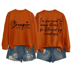 Detail view of orange cotton sweatshirt featuring artistic printed slogan on front and back
