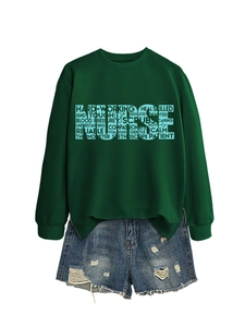 Flat lay of a dark green crewneck nurse sweatshirt with word cloud print and denim shorts