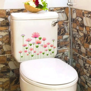 Detail of pink lotus floral stickers on a white toilet tank with bathroom tile background
