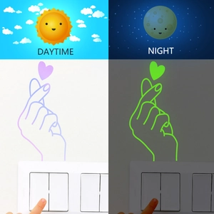 Luminous heart gesture wall sticker for light switches showing day and night glow effect