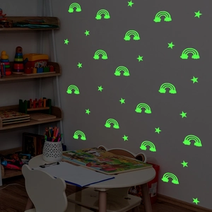 Luminous rainbow and stars wall stickers glowing green in a dark children room setting