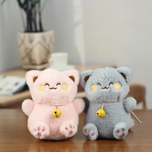Close-up of cute plush cat keychains with embroidery details and yellow bells on wood