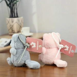 Detail shot of cute gray and pink plush cat keychains with star-shaped clips on wood