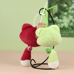 Détail de porte-clés chat en peluche rouge et vert avec cloches et sangles en silicone