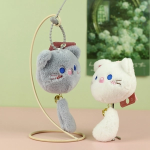 Close-up of cute plush cat head charms with gold bells and soft textured fur