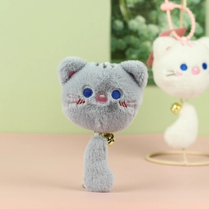 Close-up of grey plush cat pendant with embroidered blue eyes and golden bell accessory