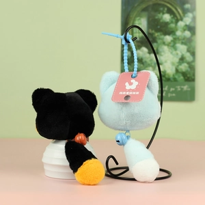 Détail de breloques chat en peluche noir et bleu clair avec longues queues et clochettes