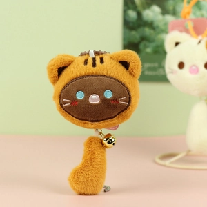 Close-up of fluffy cat plush keychain with embroidery details and golden bell charm