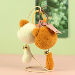 Detail of plush cat charm with golden bell and long tail on a colorful beaded chain