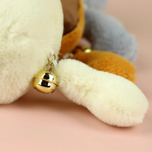 Close-up of golden bell detail on soft plush cat keychain with white and brown faux fur